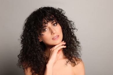 Photo of Beautiful young woman with long curly hair on light grey background