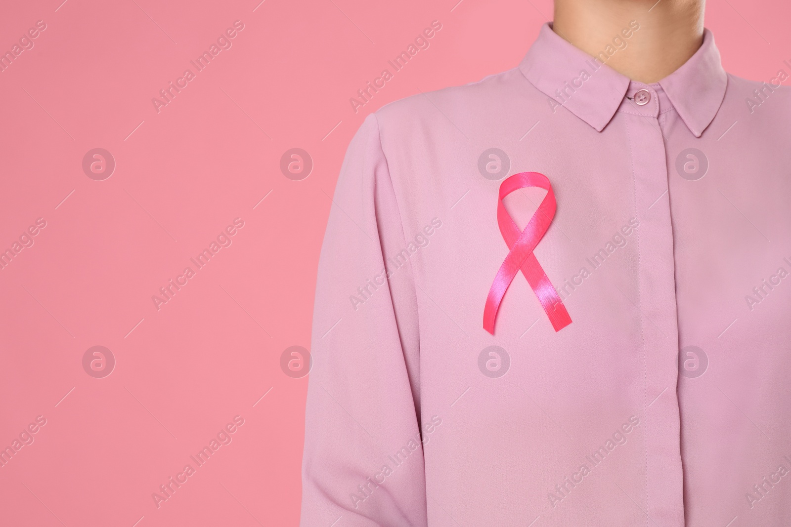 Photo of Closeup view of woman with pink ribbon on color background, space for text. Breast cancer awareness