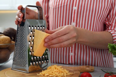 Woman grating cheese at kitchen table, closeup