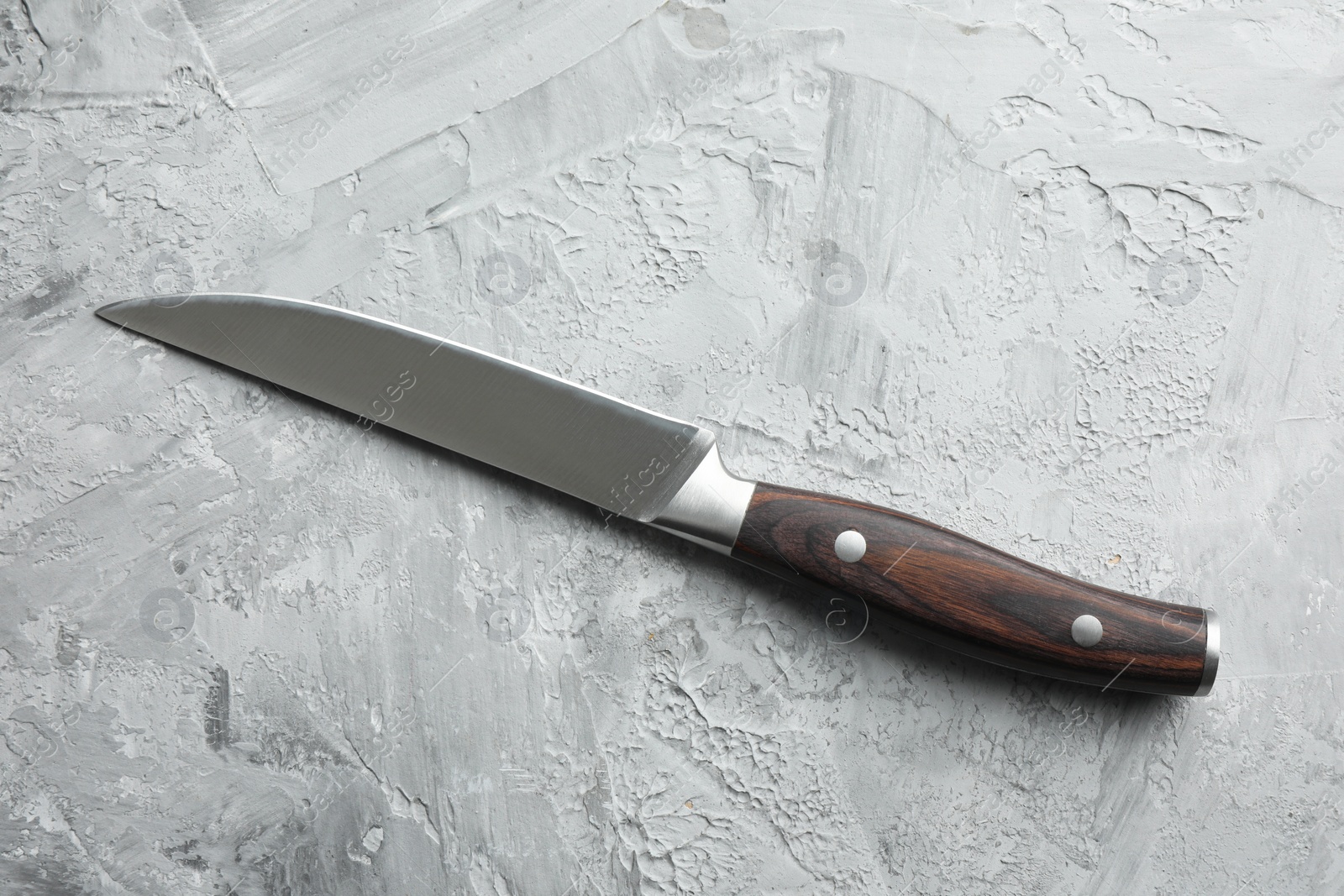 Photo of One knife on grey textured table, top view