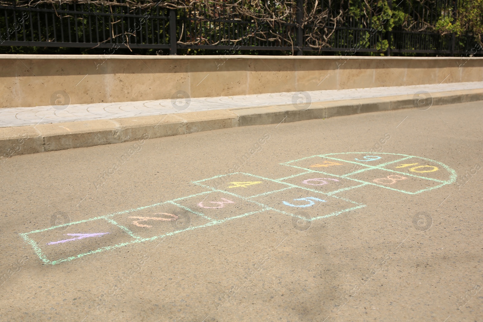 Photo of Hopscotch drawn with colorful chalk on asphalt outdoors