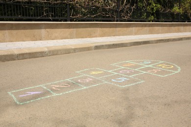 Hopscotch drawn with colorful chalk on asphalt outdoors