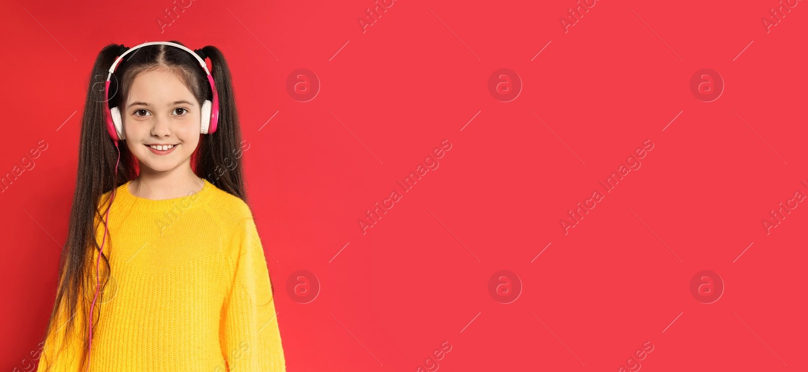 Image of Little girl listening to music with headphones on red background, space for text. Banner design