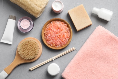 Photo of Flat lay composition with spa cosmetics and towel on grey background