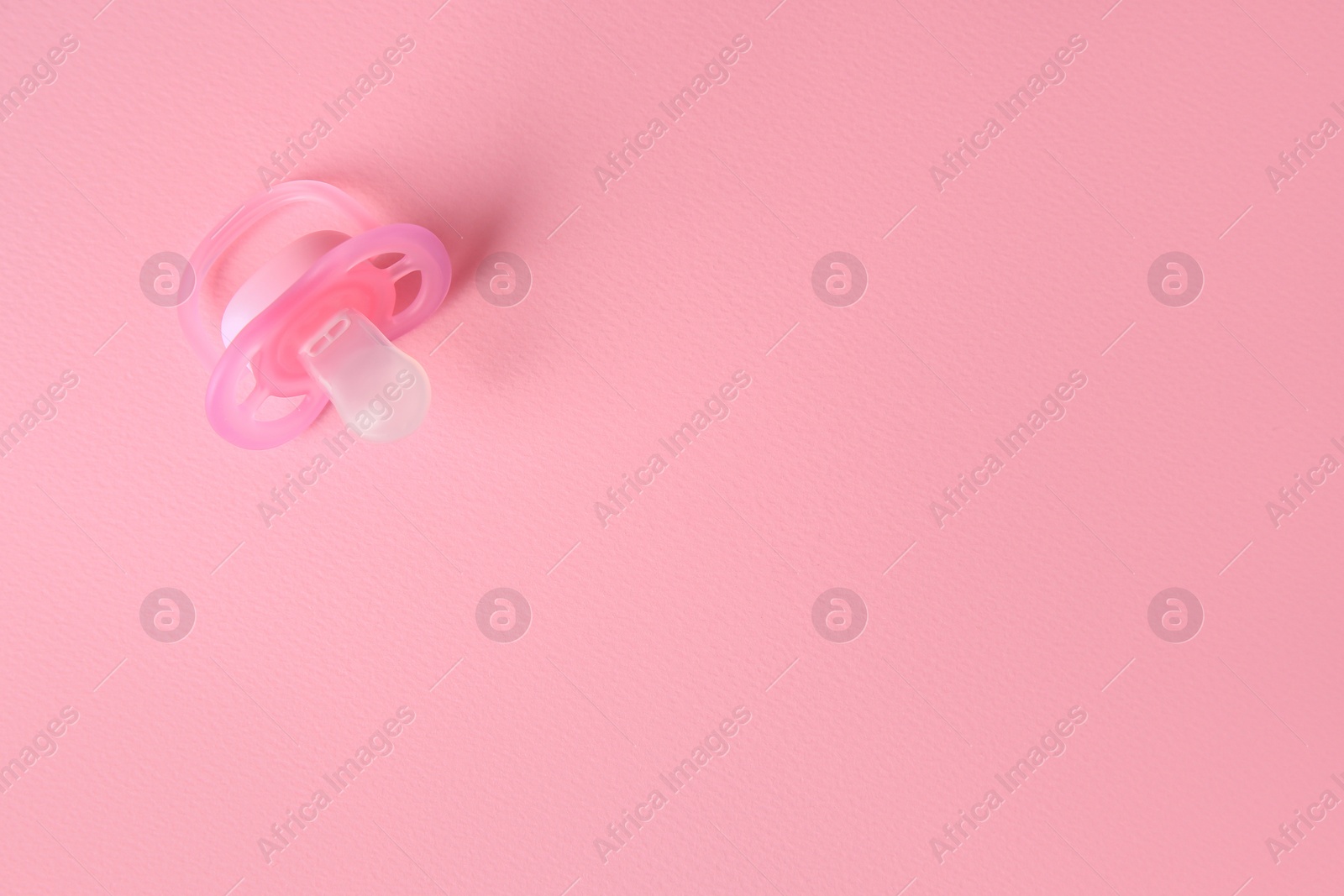 Photo of New baby pacifier on pink background, top view. Space for text