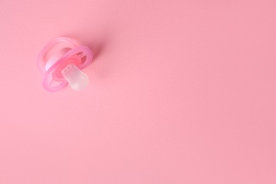 Photo of New baby pacifier on pink background, top view. Space for text