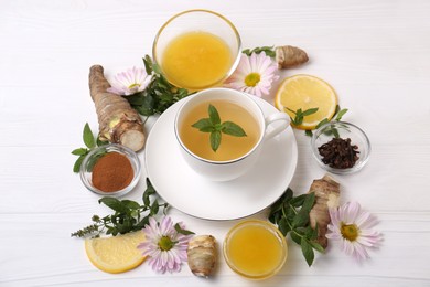 Photo of Flat lay composition with cup of delicious tea, honey and ginger on white wooden table