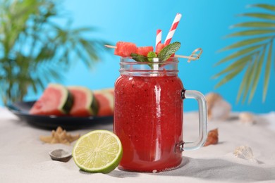 Photo of Tasty watermelon drink with lime in mason jar on sand