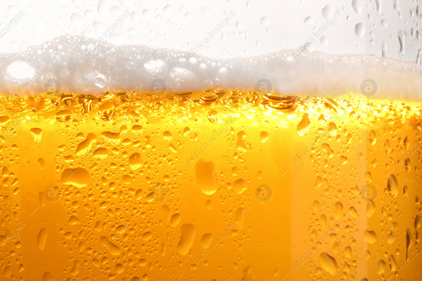 Photo of Glass of tasty cold beer with foam and condensation drops on white background, closeup