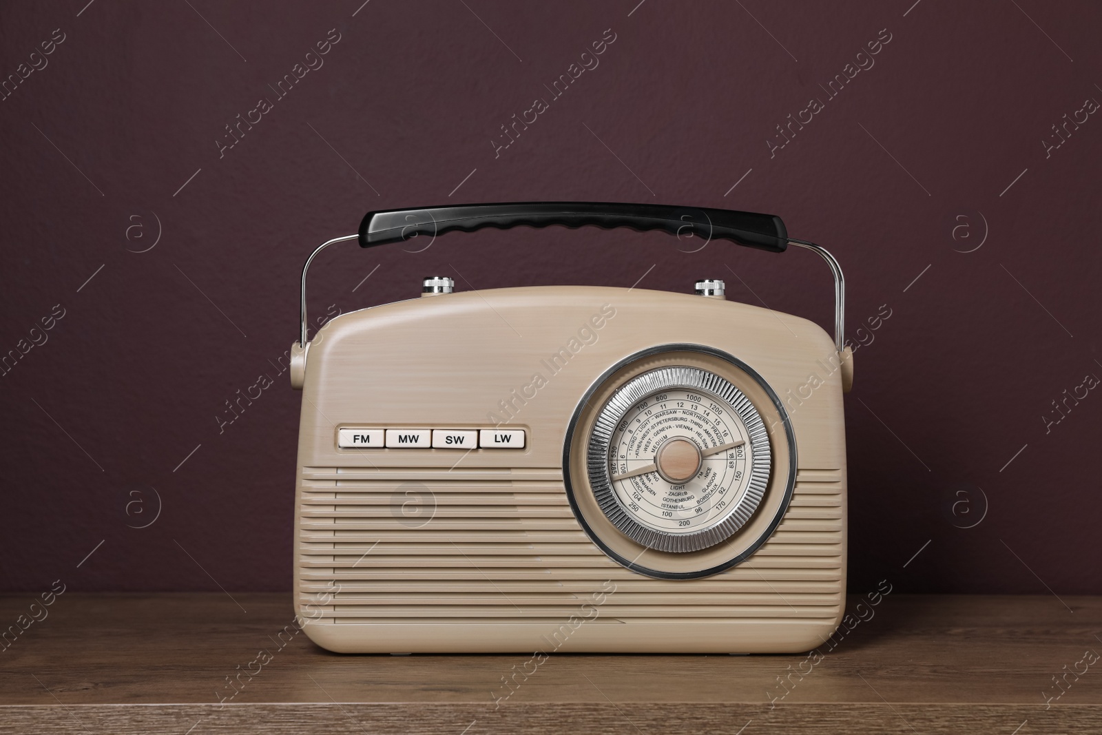 Photo of Retro radio receiver on wooden table against brown background