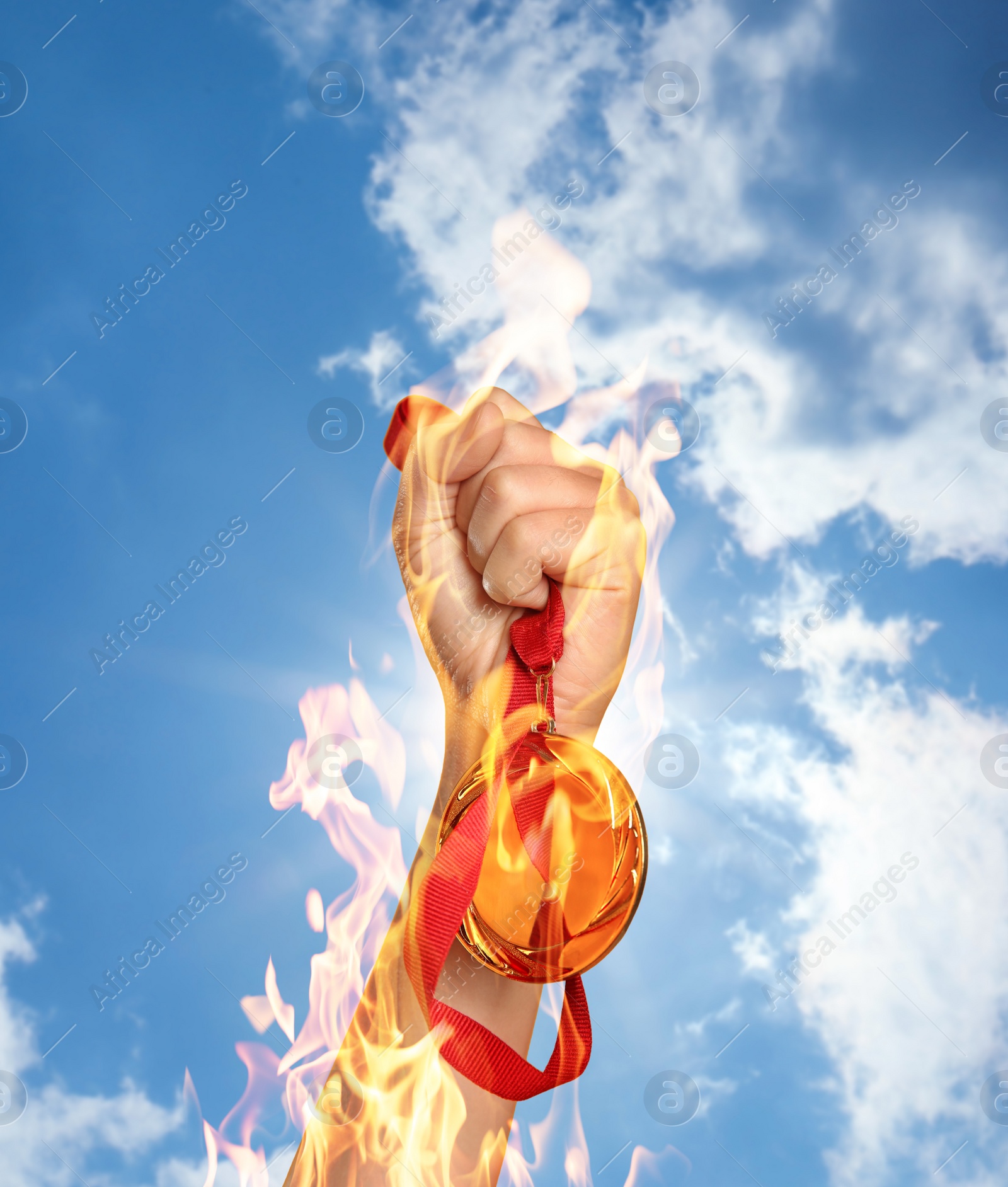 Image of Winner raising hand with gold medal from fire flames up to sky, closeup