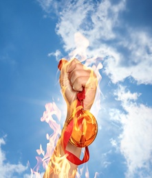 Image of Winner raising hand with gold medal from fire flames up to sky, closeup