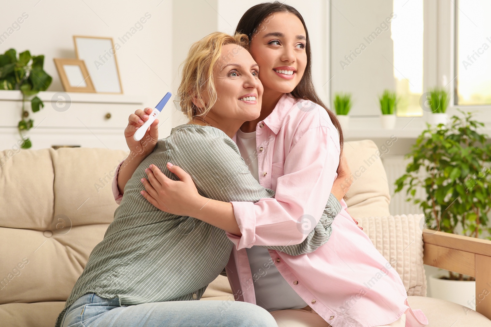 Photo of Happy pregnant woman spending time with her mother at home. Grandparents' reaction to future grandson