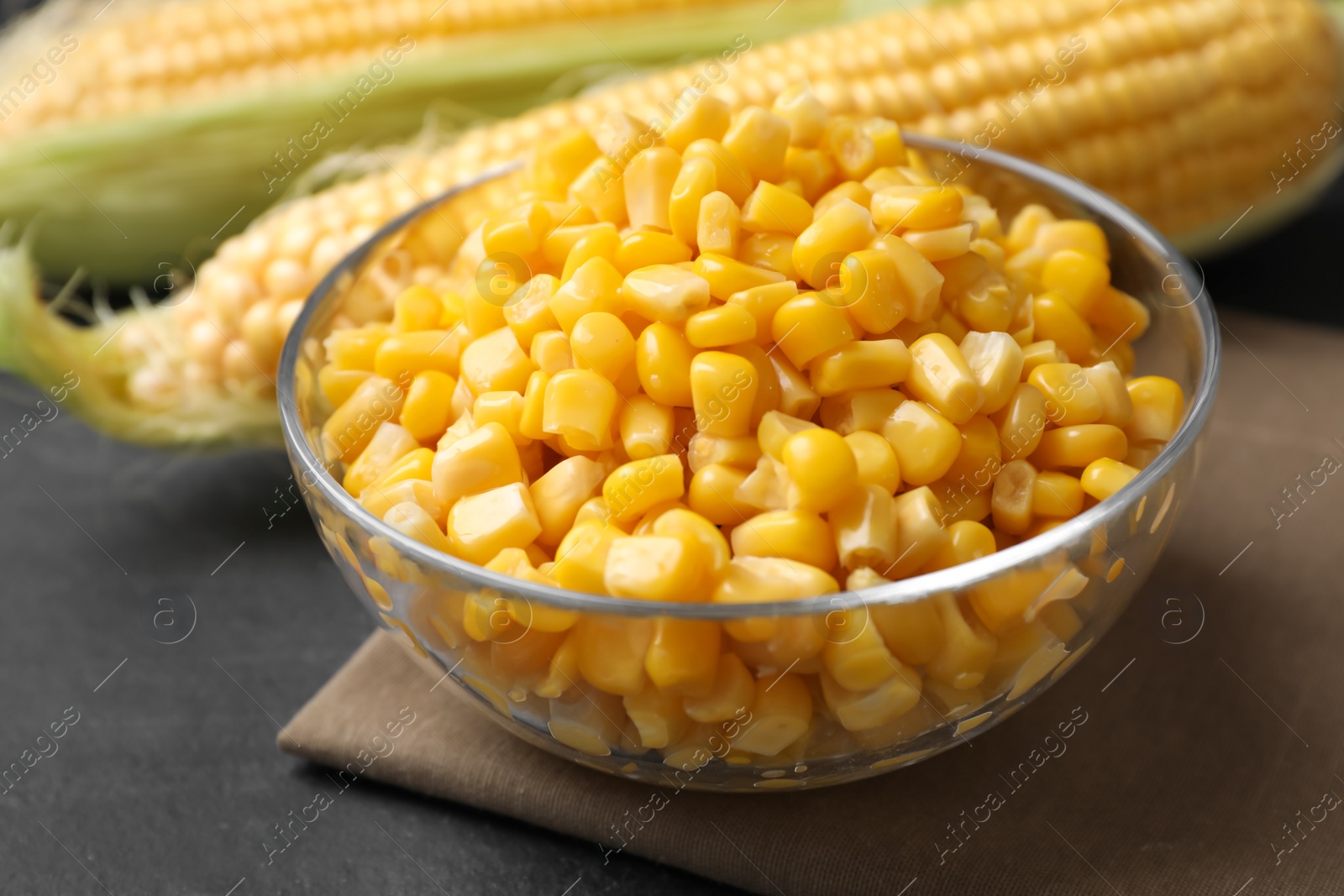 Photo of Bowl of preserved corn on grey table, closeup