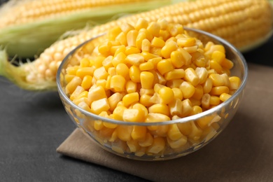 Bowl of preserved corn on grey table, closeup