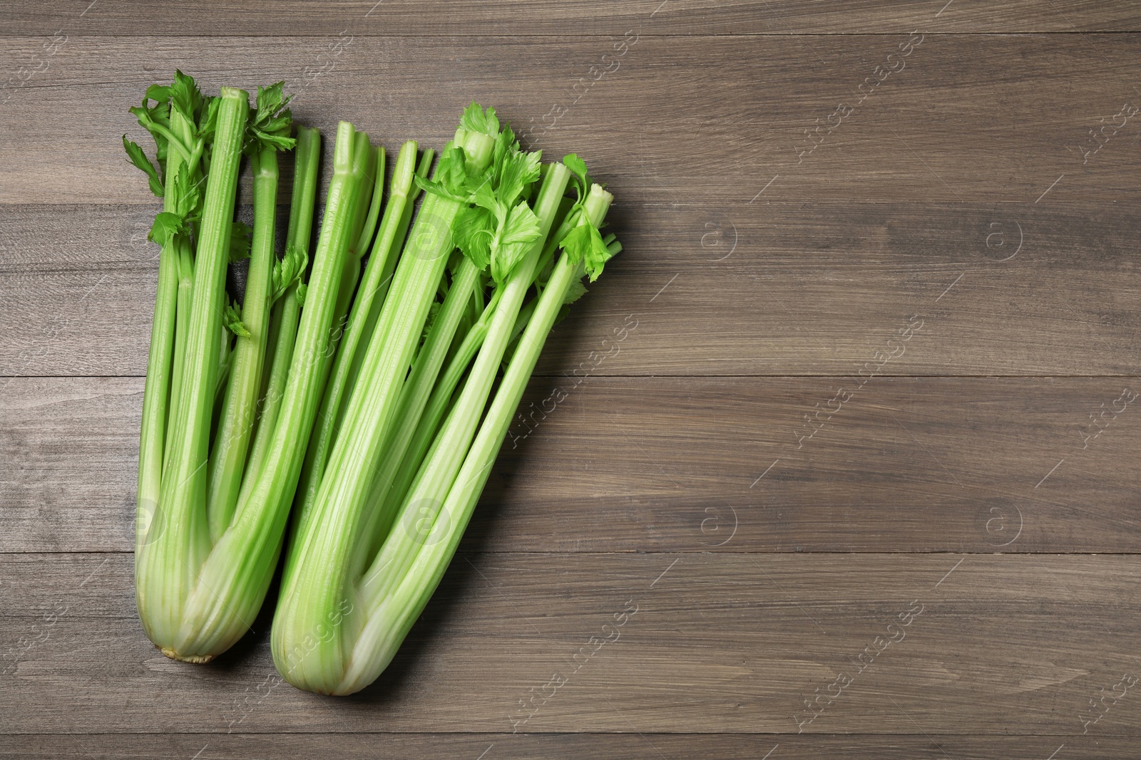 Photo of Fresh green celery stalks on wooden table, flat lay. Space for text