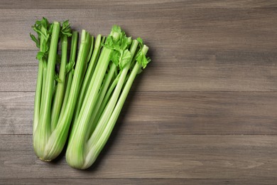 Fresh green celery stalks on wooden table, flat lay. Space for text