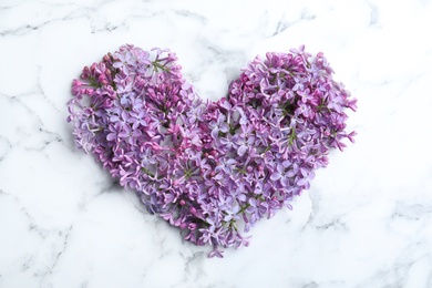 Photo of Heart made of blossoming lilac on marble table, flat lay. Spring flowers