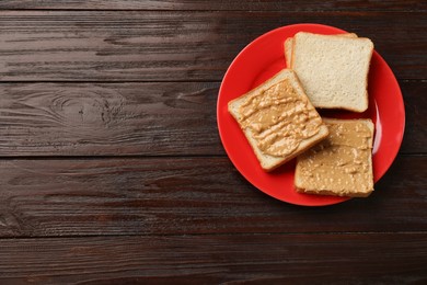 Photo of Delicious toasts with peanut butter on dark wooden table, top view. Space for text