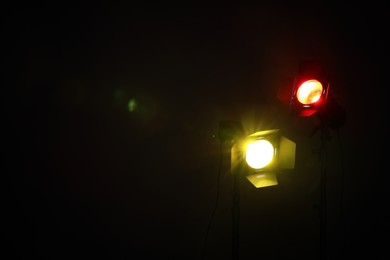 Photo of Bright colorful spotlights in darkness, space for text