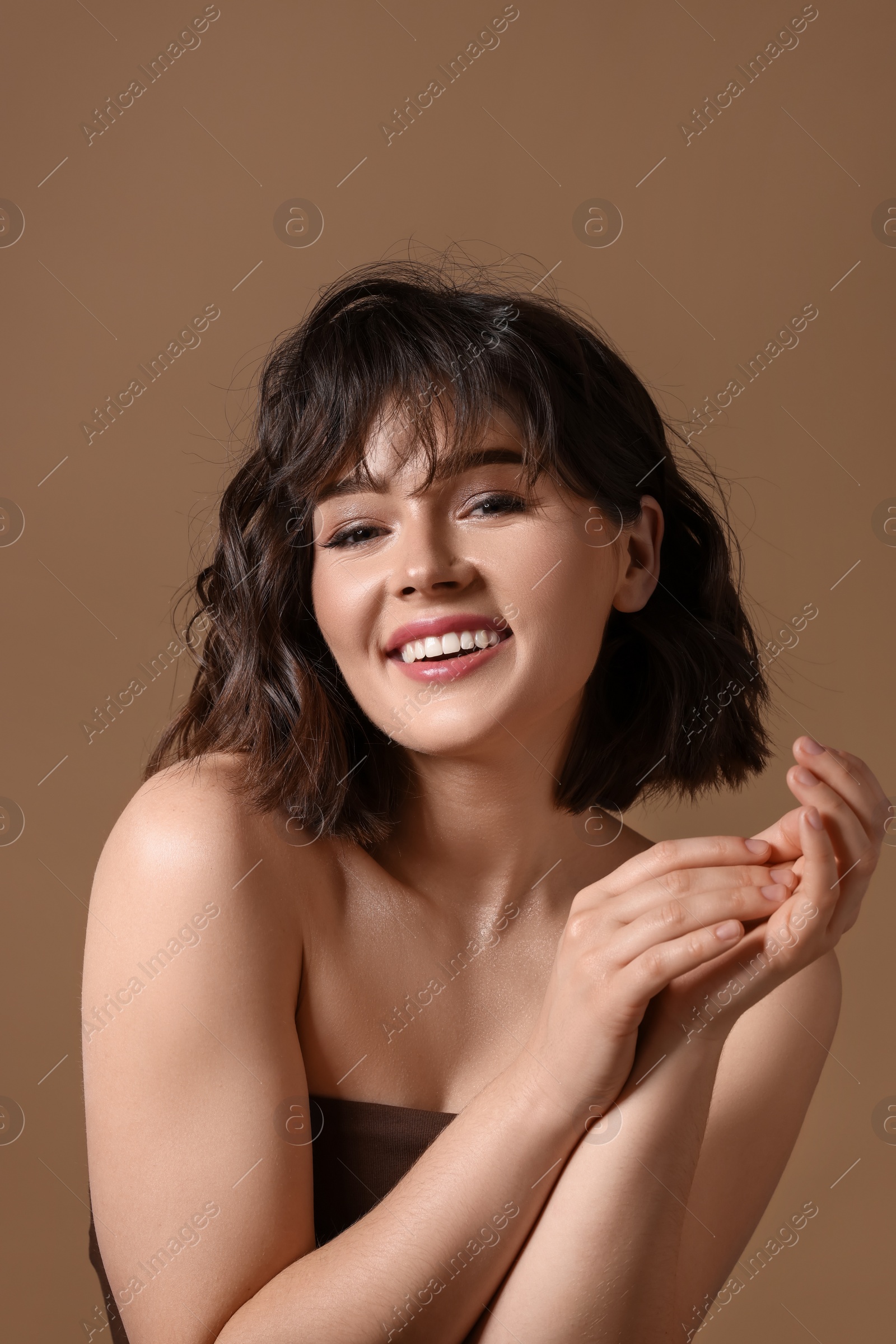 Photo of Portrait of beautiful young woman with wavy hairstyle on brown background