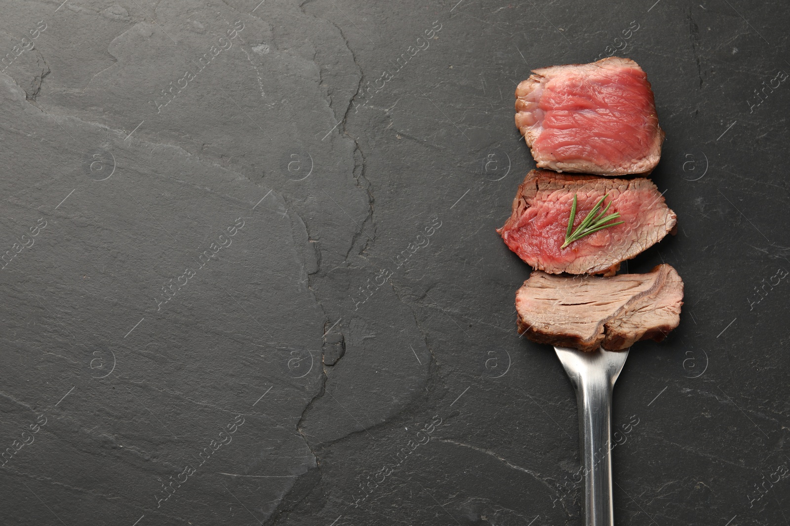 Photo of Delicious sliced beef tenderloin with different degrees of doneness on black table, top view. Space for text