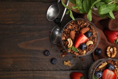 Photo of Tasty granola, berries, nuts and mint on wooden table, flat lay. Space for text