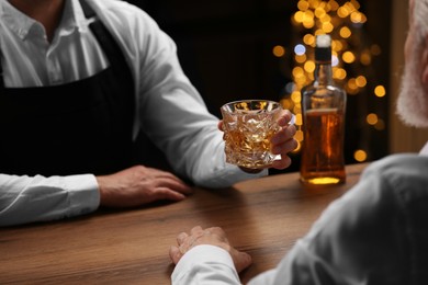Photo of Bartender giving glass of whiskey to customer at bar counter, closeup