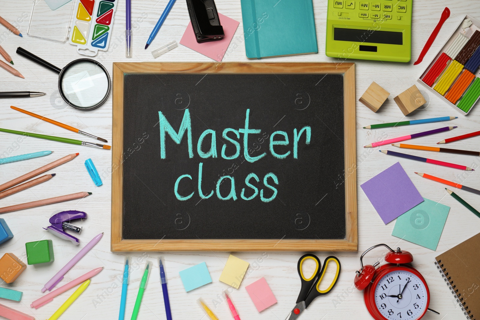 Photo of Blackboard with words Master Class surrounded by different stationery on white wooden table, flat lay