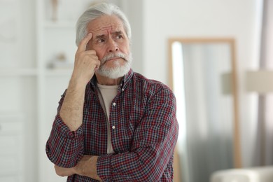 Portrait of thoughtful grandpa with grey hair indoors