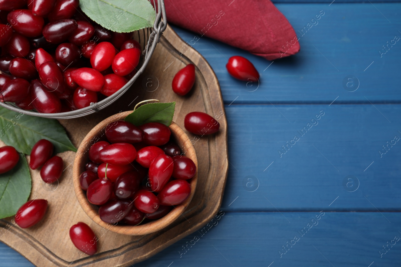 Photo of Fresh ripe dogwood berries on blue wooden table, flat lay. Space for text