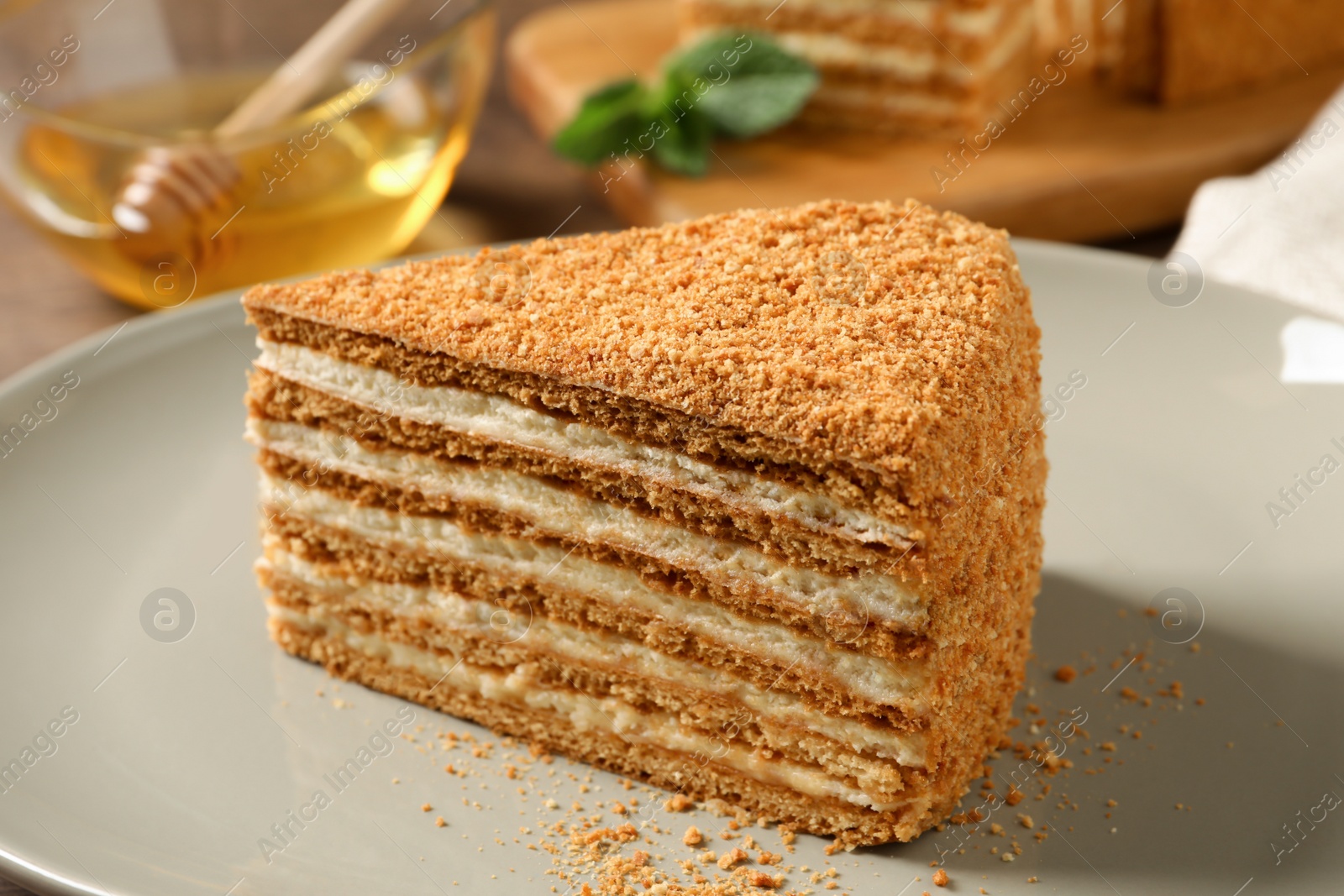 Photo of Slice of delicious layered honey cake on plate, closeup