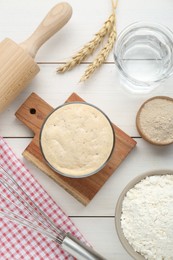 Leaven, flour, water, rolling pin and ears of wheat on white wooden table, flat lay