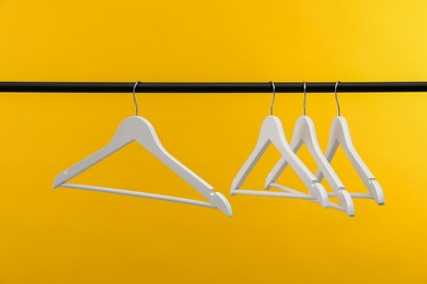 Photo of Empty clothes hangers on rack against orange background