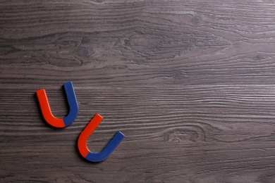 Photo of Red and blue horseshoe magnets on dark grey wooden background, flat lay. Space for text