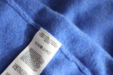 Clothing label in different languages on blue garment, closeup