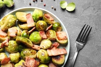 Image of Delicious fried Brussels sprouts with bacon served on grey table, flat lay