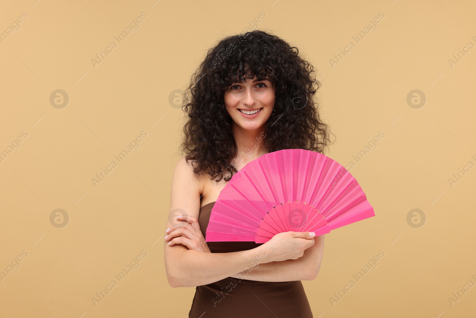 Photo of Happy woman holding hand fan on beige background