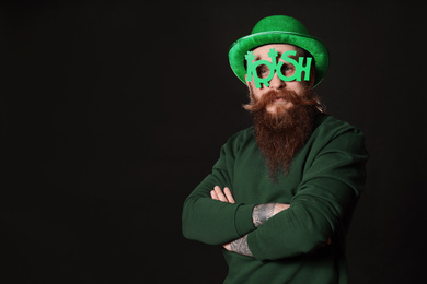 Bearded man in party glasses on black background. St. Patrick's Day celebration