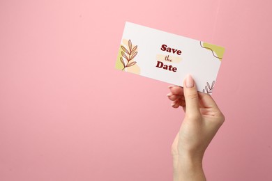 Woman holding beautiful card with Save the Date phrase on pink background, closeup. Space for text