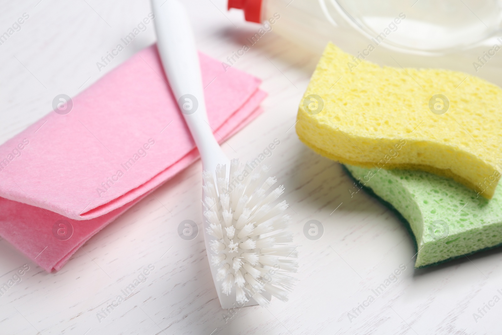 Photo of Cleaning supplies for dish washing on white wooden table, closeup