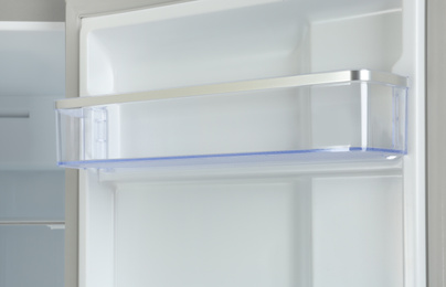 Photo of Door shelf of empty modern refrigerator, closeup view