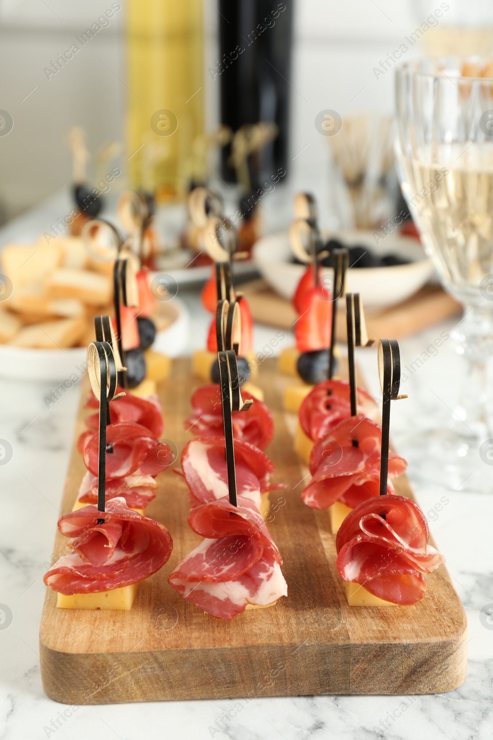 Photo of Different tasty canapes on white marble table, closeup