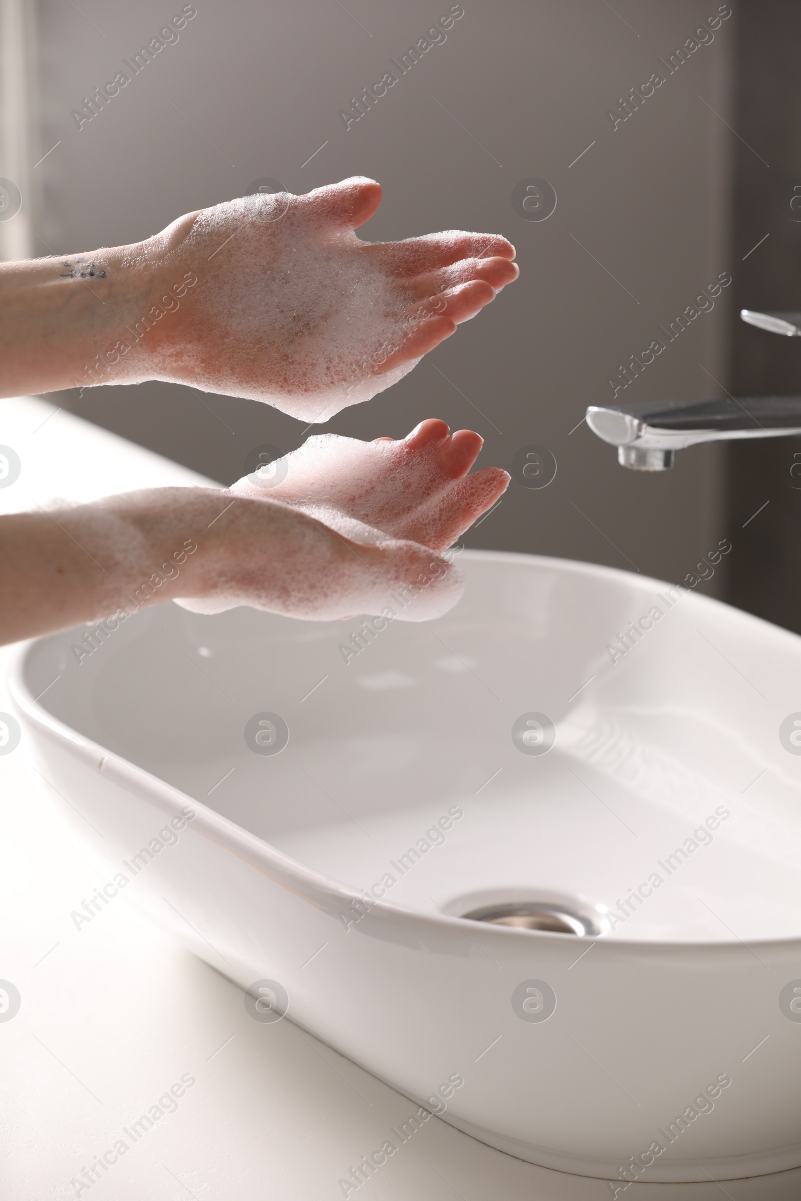 Photo of Woman washing hands with cleansing foam near sink in bathroom, closeup