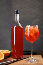 Aperol spritz cocktail and ice cubes in glass and bottle on wooden table