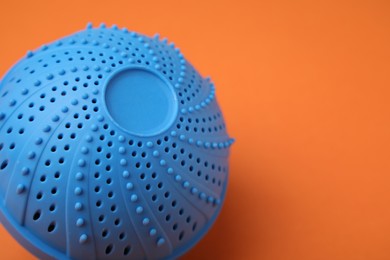 Photo of Laundry dryer ball on orange background, closeup. Space for text