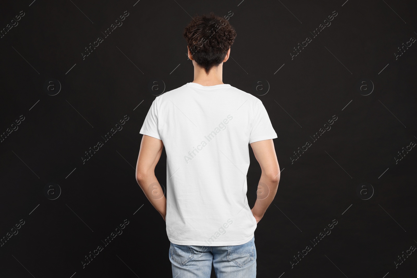 Photo of Man wearing white t-shirt on black background, back view. Mockup for design