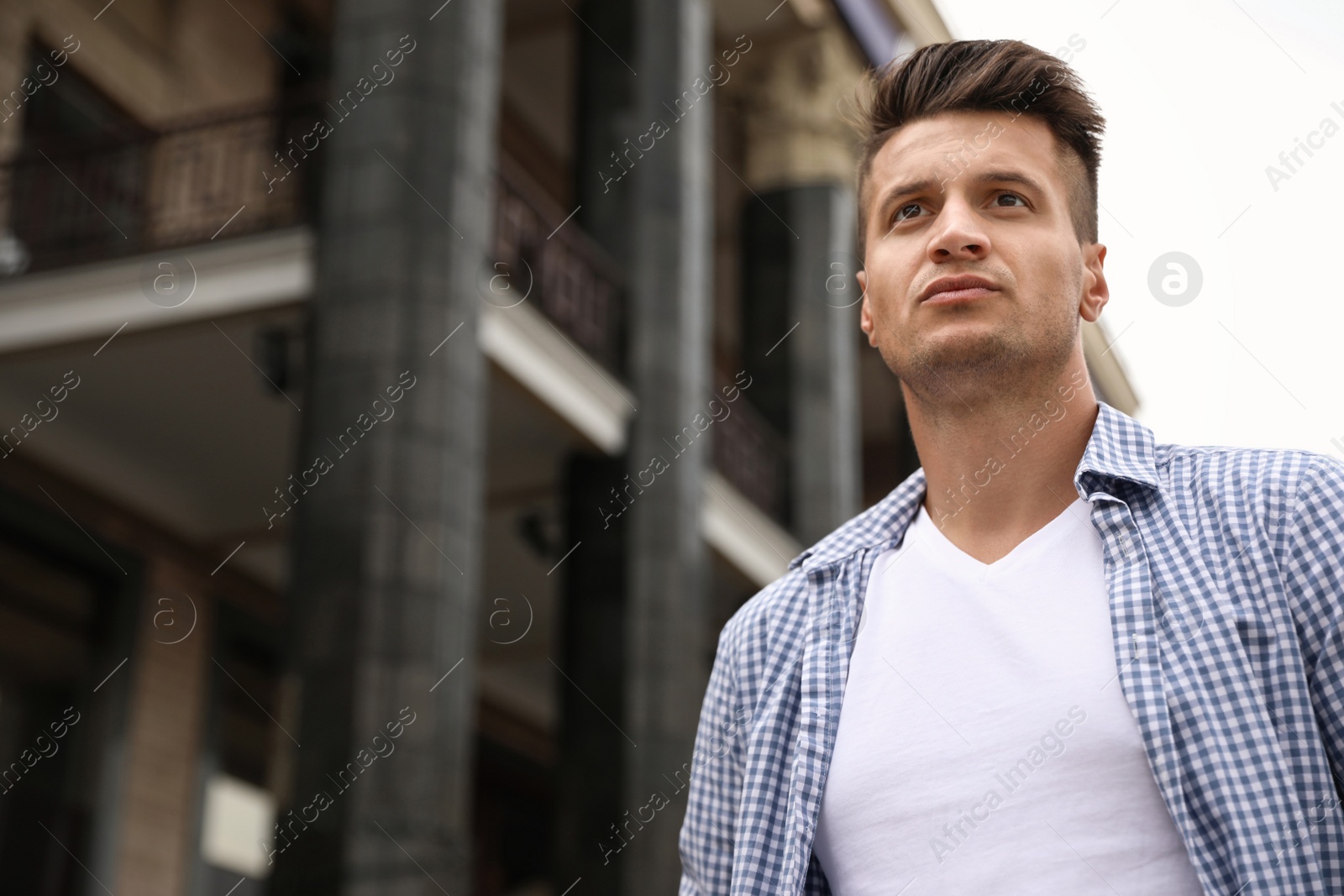 Photo of Portrait of handsome young man on city street. Space for text