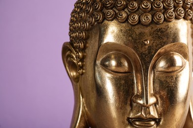 Photo of Beautiful golden Buddha sculpture on violet background, closeup. Space for text