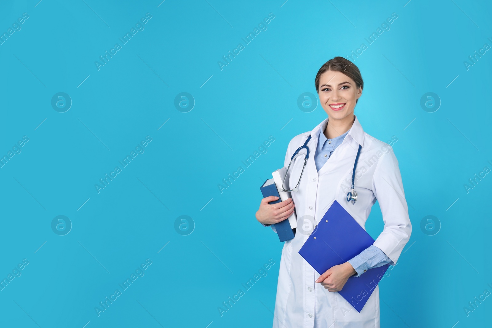 Photo of Young medical student with clipboard and books on color background. Space for text